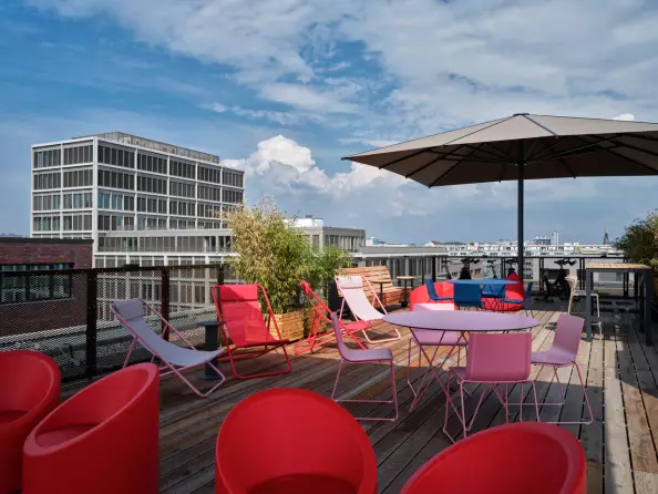 Foto: Dachterasse von Urban Loft Berlin. mit roten Sesseln und Sonnenstühlen